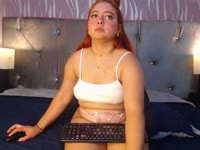 A young, flirtatious, and very charismatic redhead with a spontaneous personality who enjoys talking and connecting with people. She has a curvaceous figure, a striking presence, and a feminine style that combines sweetness, confidence, and playfulness. She